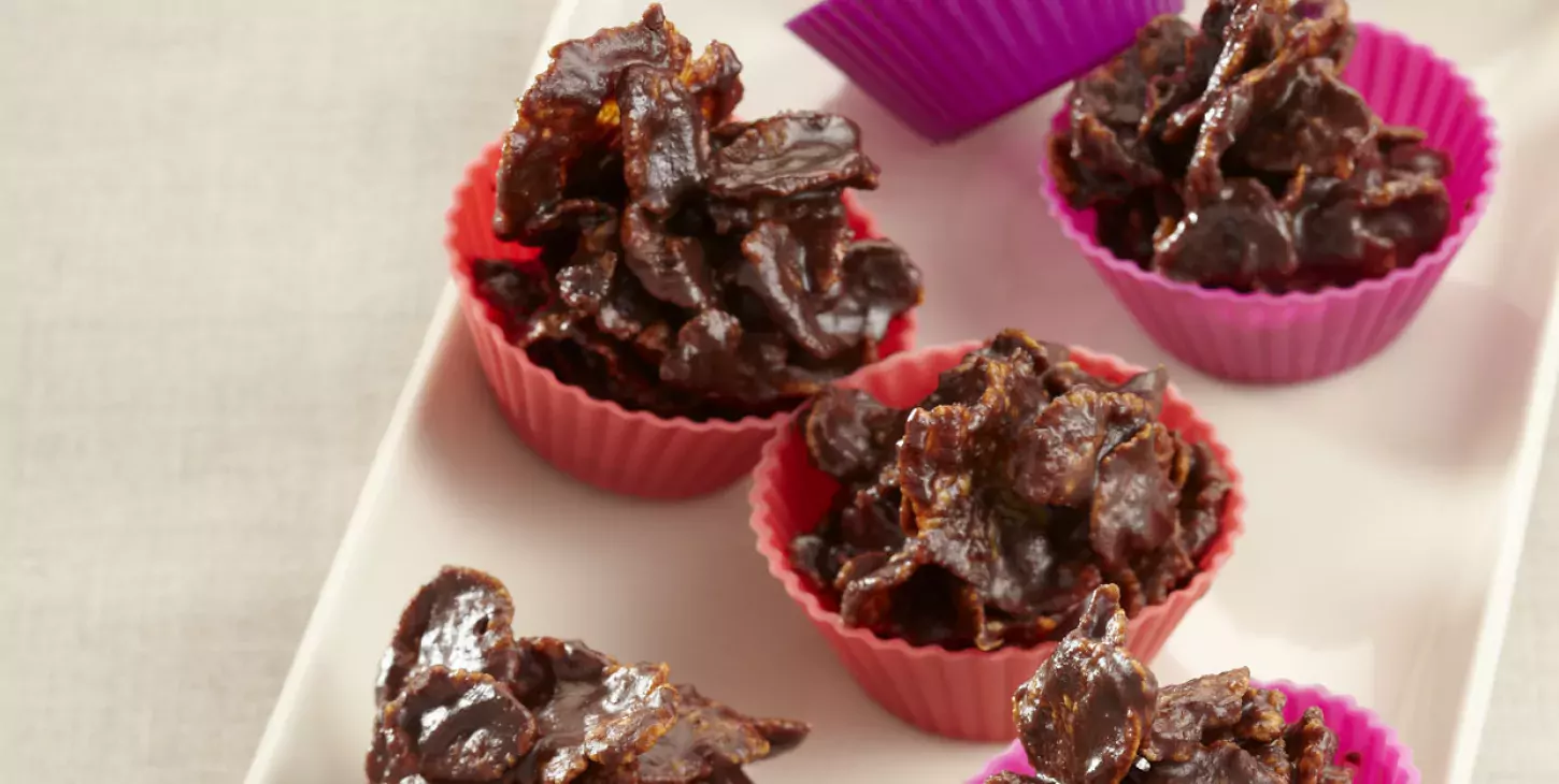 Petits tas de roses des sables au chocolat et aux corn flakes posés sur une feuille de cuisson