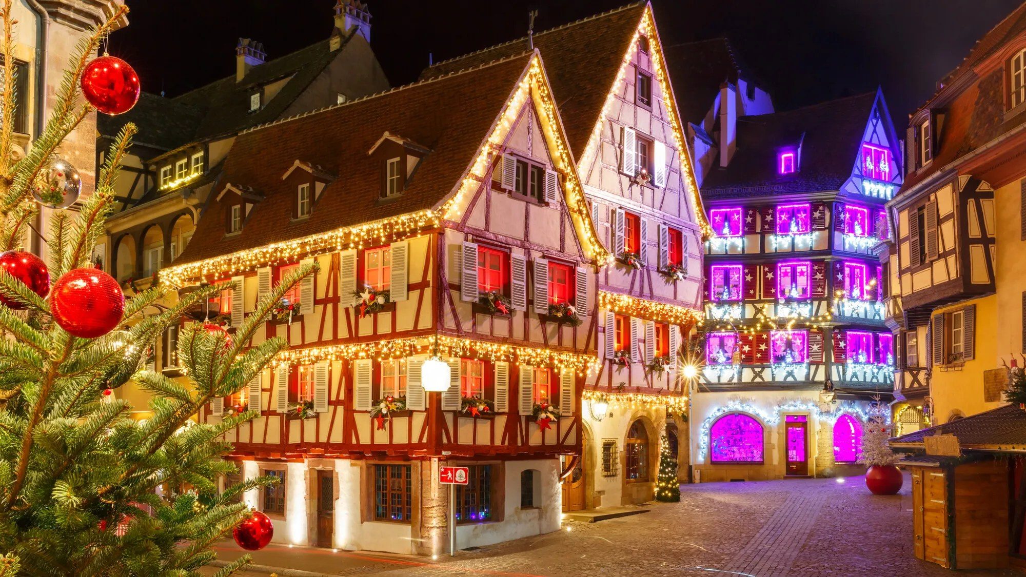 Maisons à colombages illuminées près d'un marché de Noël à Colmar